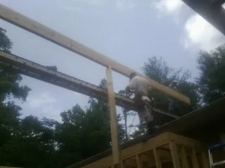 Carpenter setting a ridge beam over a new addition frame — Ice Dam Removal by Roofing Brothers in Bayard