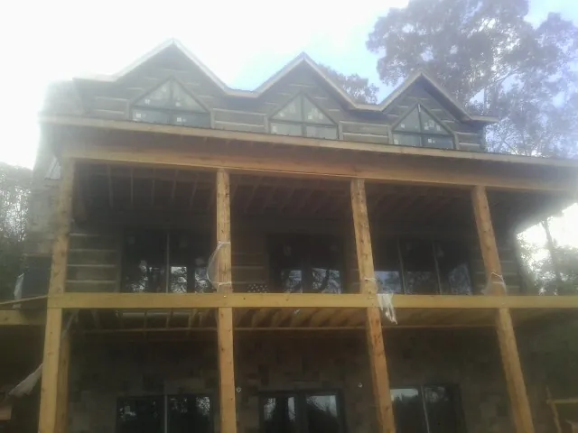 Dormers and porch framing on a large log home under construction — Roof Coating work by our crew in Bayard