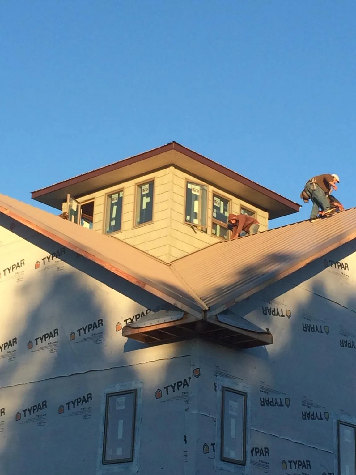 Roofers working around a rooftop cupola on a new metal roof at sunset — Roof Waterproofing in Bayard by Roofing Brothers